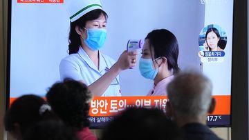 People watch a TV screen showing a file image of North Korean leader Kim Jong Un, right, during a news program at a train station in Seoul, South Korea,