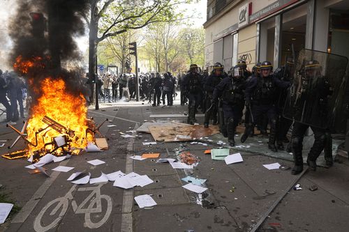 Riot police officers walk by a fire during a demonstration Thursday, April 6, 2023 in Paris.  