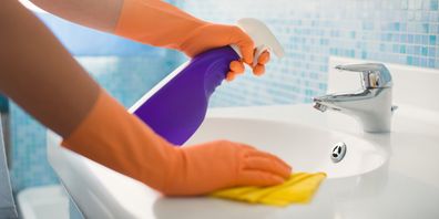 A woman cleaning the bathroom sink