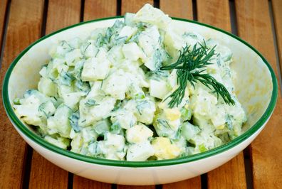 Delicious Freshly Made Creamy Potato Salad Garnished with Dill in Beige Bowl closeup on Wooden Plank background