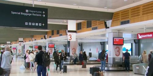 Returning travellers mull around a Qantas baggage claim.