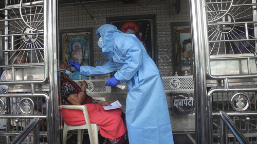 A health worker takes a swab test of a women at a temple in Mumbai, India, Saturday, July 18, 2020. India crossed 1 million coronavirus cases on Friday, third only to the United States and Brazil, prompting concerns about its readiness to confront an inevitable surge that could overwhelm hospitals and test the country's feeble health care system. (AP Photo/Rafiq Maqbool)