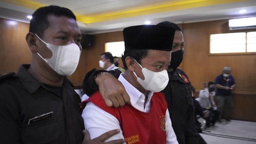 Indonesian school principal Herry Wirawan, centre, has been convicted of raping at least 13 girls and has been sentenced to death. 