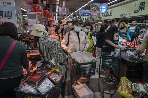 People crowd as they shop for food at a supermarket in Chaoyang District in Beijing, China