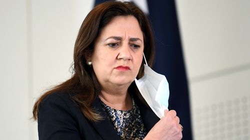 Queensland Premier Annastacia Palaszczuk takes her mask off during a press conference