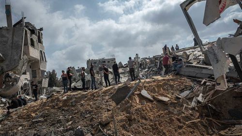 Men walk on the rubble of a residential building in Gaza City destroyed by an Israeli airstrike.