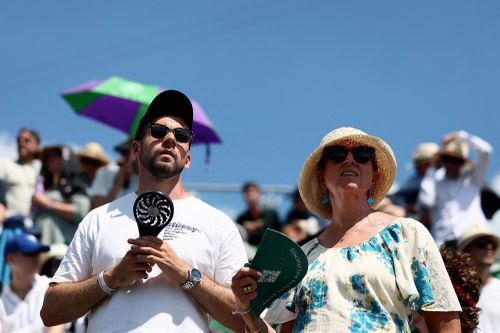 Wimbledon tennis spectators use handheld fans to cool themselves down during the first round match between Russia's Daniil Medvedev and France's Benjamin Bonzi in London on June 30, 2025.