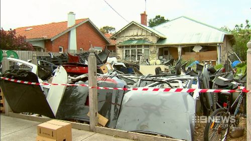 The front yard of the Melbourne home is piled high with car parts, white goods and tin drums. (9NEWS)