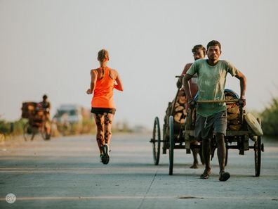 Samantha Gash running past a man pulling a rickshaw in India.