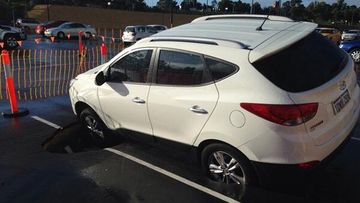A social media post showed the front and back tyres of a white Hyundai stuck in the hole. (Supplied)