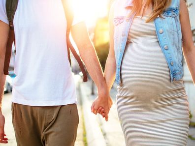 Man walking hand in hand with pregnant partner