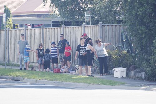 Residents stand along McClelland Drive, Skye, as a fire burns in the bushland behind their homes. (AAP)