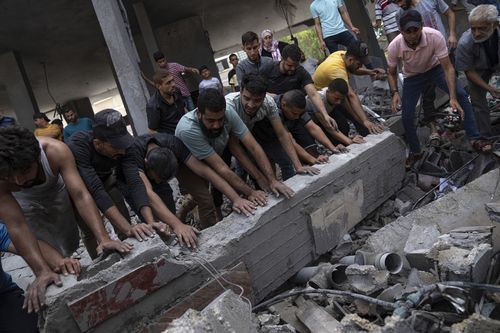 Palestinians look for survivors in a building destroyed in Israeli bombardment in Rafah refugee camp in Gaza Strip on Tuesday, Oct. 17, 2023.