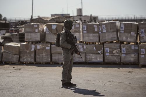 FILE - An Israeli soldier stands beside humanitarian aid packages awaiting pickup on the Palestinian side of the Kerem Shalom crossing in the Gaza Strip, Thursday, July 24, 2025, during a media tour organized by the Israeli army. (AP Photo/Ohad Zwigenberg, file)