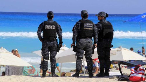 Police stand guard on the beach in Cancun.