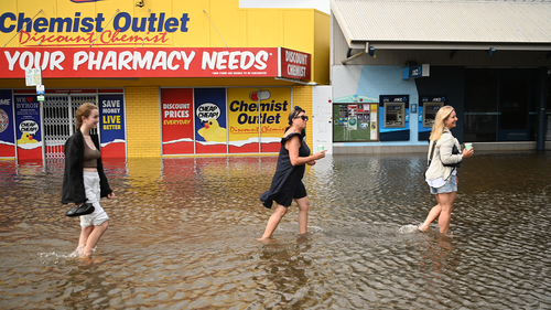 People walk through floodwater on March 30, 2022 in Byron Bay, Australia.