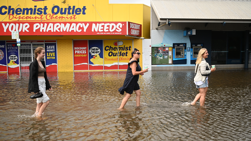 Des personnes marchent dans les eaux de crue le 30 mars 2022 à Byron Bay, en Australie.