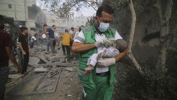 A Palestinian medic takes a baby pulled out of buildings destroyed in the Israeli bombardment