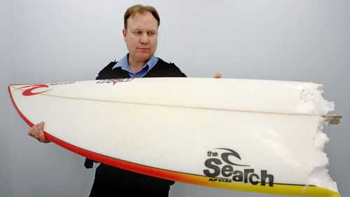 A Margaret River policeman holds a surfboard which was snapped in half during a fatal shark attack at Gracetown beach, Western Australia, August, 2010. (AAP) 