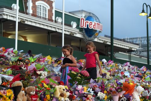 Young girls walk through a floral tribute outside the Dreamworld Theme Park on the Gold Coast, Friday, Oct. 28, 2016. (AAP)