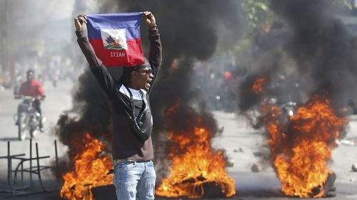 Un manifestant brandit un drapeau haïtien lors de manifestations exigeant la démission du Premier ministre Ariel Henry à Port-au-Prince, en Haïti, le vendredi 1er mars 2024.