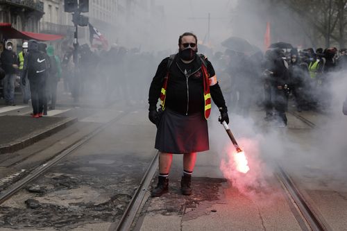 A demonstrator holds a flare during a protest Thursday, April 6, 2023 in Nantes, western France 