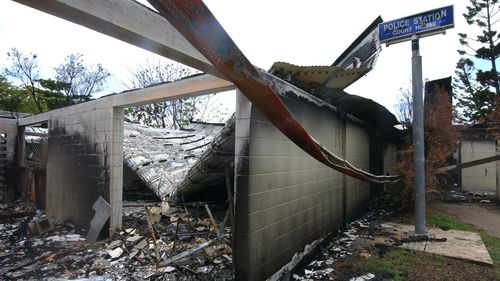 The burn-out remains of the local police station after angry rioters set it ablaze with police officers still inside. (AAP)