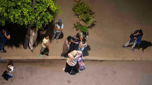 Oamenii se acoperă și verifică știrile de pe telefoanele mobile după cutremurul de la Rabat, Maroc.