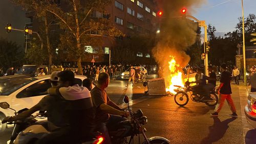 A police motorcycle and a trash bin are burning during a protest over the death of Mahsa Amini, a 22-year-old woman who had been detained by the nation's morality police, in downtown Tehran, Iran. This photo was taken by an individual not employed by the Associated Press on September 19, 2022 and obtained by the AP outside Iran.