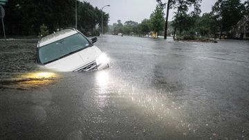 An SUV is stranded in a ditch along a stretch of street flooding during a severe storm Thursday in Spring, Texas.