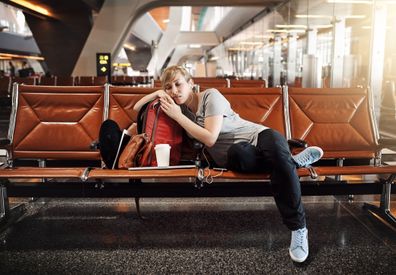 Full length shot of an attractive young woman sleeping in an airport