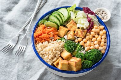 Nourishing buddha bowl with tofu, quinoa and vegetables. Healthy eating, healthy lifestyle, vegan food, vegetarian diet, modern lifestyle concept. Colorful buddha bowl on table. Selective focus