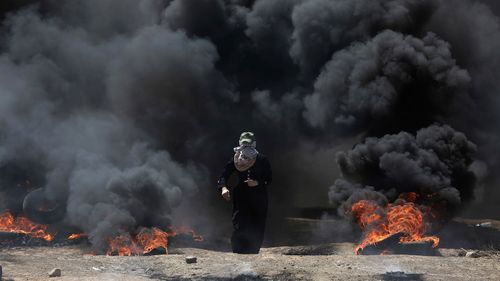A woman walks through smoke at the Gaza protests on the Israel border ahead of the US Embassy opening in Jerusalem. (AP)
