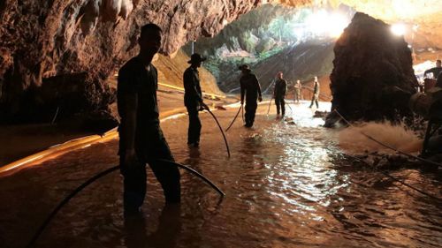 Thai rescue teams arrange a water pumping system at the entrance to the flooded cave complex. Picture: AAP