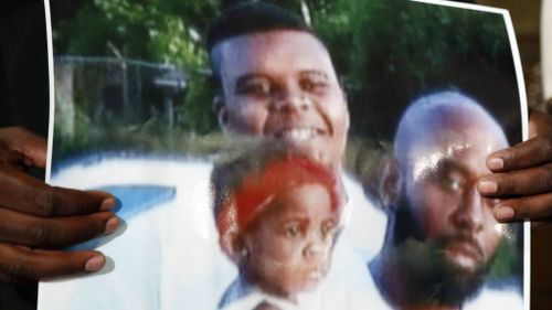 A family member holds a photo of slain 18-year-old Michael Brown, shot dead by a police officer on August 9. (AAP)