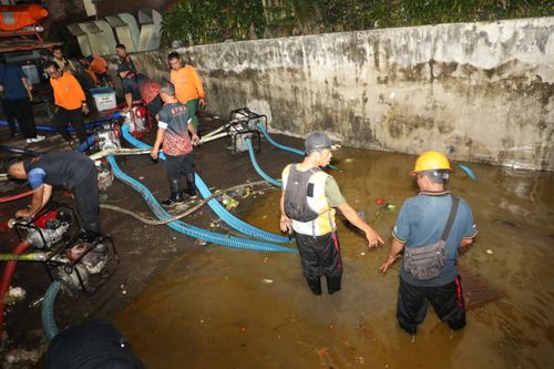 Equipes de limpeza na sucção da água que ainda é mantida no estacionamento de Pasar Badung.