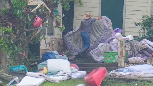 A man removes bedding from sleeping quarters at Camp Mystic along the banks of the Guadalupe River in Texas