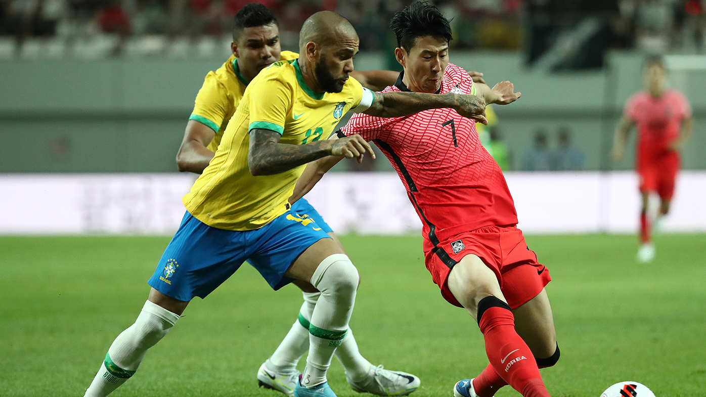 Dani Alves competes for the ball with Son Heung-min during an international friendly match between Brazil and  South Korea.
