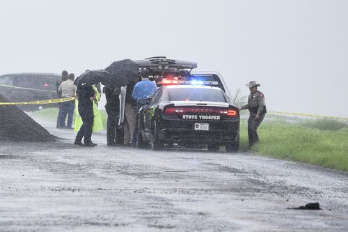 Law enforcement officers gather near the scene where the body of a woman was found near Interstate 35 north of Laredo, Texas on Saturday.
