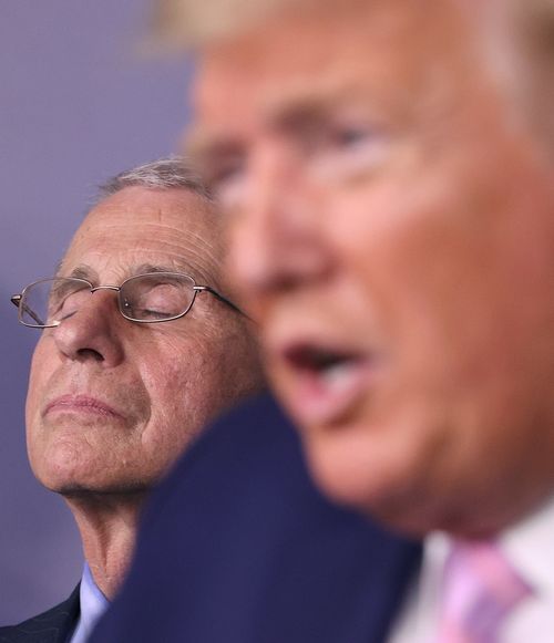 Dr Anthony Fauci listens to President Donald Trump