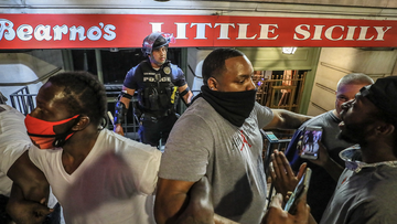 In this Thursday, May 28, 2020 photo, protesters rallying against police brutality surround a Louisville Metro Police Department officer in front of Bearno&#x27;s restaurant, in Louisville, Ky.  (Michael Clevenger/Courier Journal via AP)