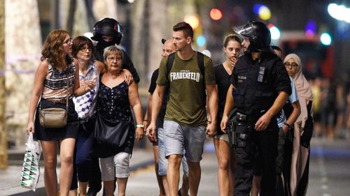 People are escorted by Spanish policemen outside a cordoned off area after a van ploughed into the crowd, killing 13 persons and injuring over 80 on Las Ramblas in Barcelona on August 17, 2017. (AFP) 