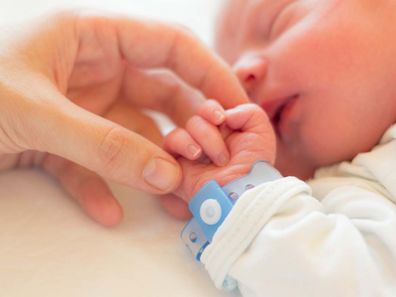 Sleeping newborn baby with adult holding it's hand