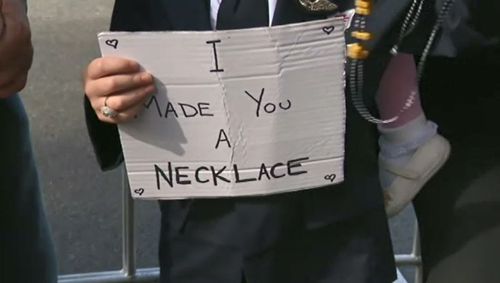 Wearing a Qantas pilot uniform, the little boy held up a sign saying ‘I made you a necklace.