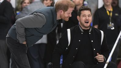 Prince Harry, the Duke of Sussex, jokes with singer Michael Buble, right, as he prepares to take a shot  during an Invictus Games wheelchair curling training camp in Vancouver, British Columbia, Friday, Feb. 16, 2024. (Darryl Dyck/The Canadian Press via AP)