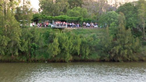 An anxious crowd looks on over the river where the man's body was eventually found.