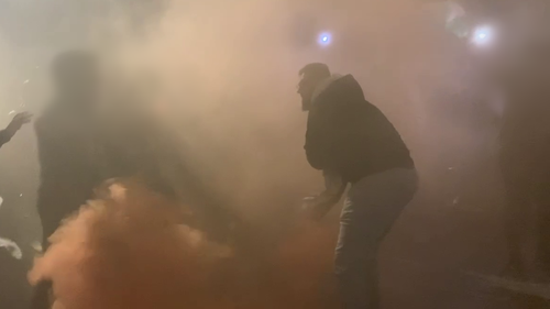 Un homme semble lancer une fusée éclairante lors d'une manifestation