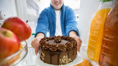 Sweet boy take big chocolate cake from fridge