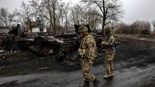 Ukrainian soldiers patrol next to a destroyed Russian tank in the village of Lukianivka near Kyiv. 