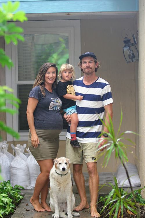 Queensland expatriate Oliver McLeod, his eight month pregnant wife Jennifer, three-year-old son Luca and dog Rubi, outside their sandbagged beach home. (AAP)